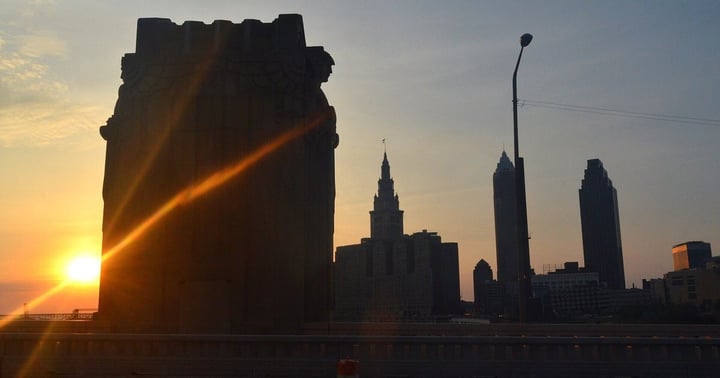 A Guardian of Traffic pylon silhouetted against the Cleveland skyline at sunset