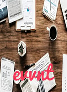 Desk with newspapers, coffee, calculators and papers