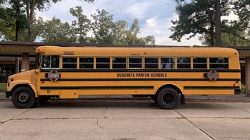 A yellow school bus parked outside an elementary school