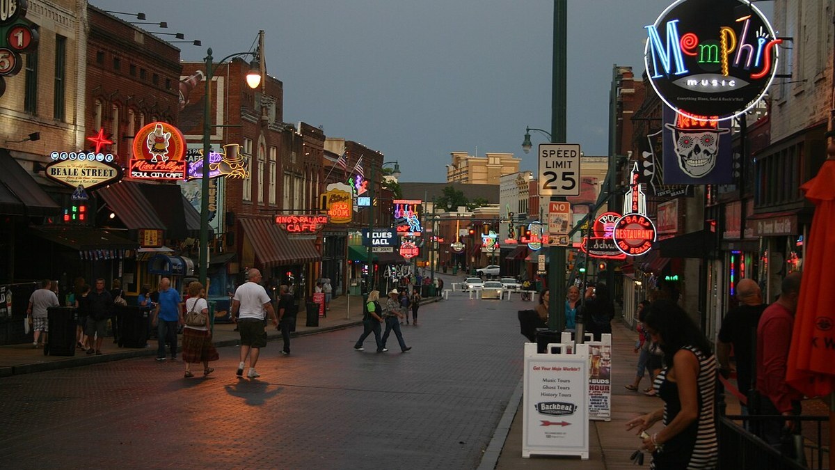 Neon signs glow along Beale Street in downtown Memphis at dusk