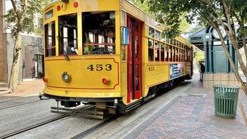 A yellow and red vintage Memphis Main Street trolley, car 453, stopped at a downtown trolley station