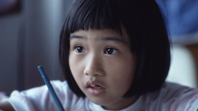 A young student concentrates while writing at a desk