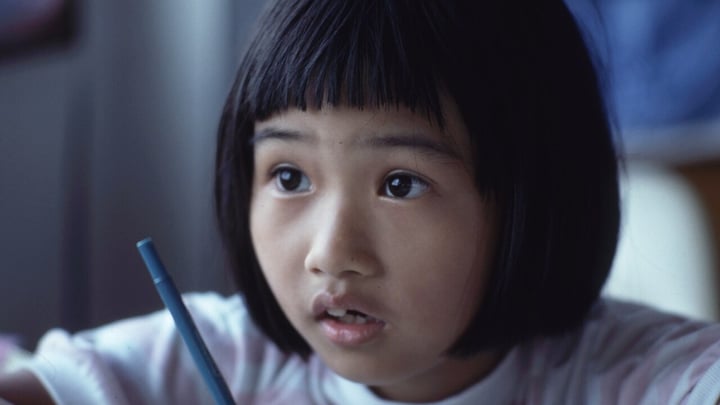 A young student concentrates while writing at a desk
