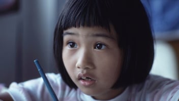 A young student concentrates while writing at a desk