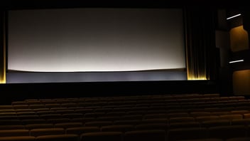 Rows of seats facing a large screen in a darkened movie theater